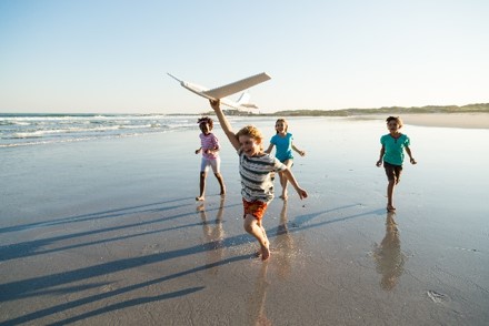 Kinder spielen mit Flugzeug am Meer