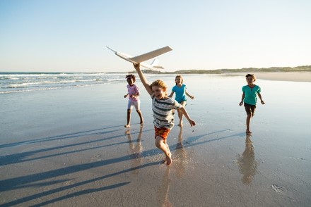 Kinder spielen mit Flugzeug am Meer